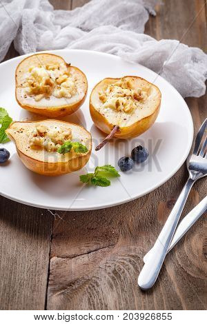 Pears baked with Ricotta cheese nuts honey and cinnamon on rustic wooden background