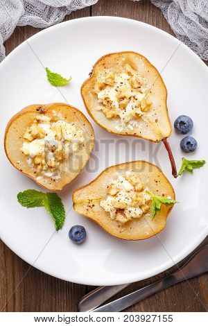 Pears baked with Ricotta cheese nuts honey and cinnamon on rustic wooden background. Top view