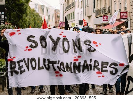 STRASBOURG FRANCE - SEPT 12 2017: Masked people with Soyons Revolutionnaires translated as Be Revolutionary poster at French Nationwide day of protest against the labor reform proposed by Emmanuel Macron Government