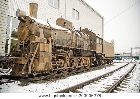 Old rusty steam locomotive on railroad in winter