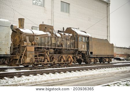 Old rusty steam engine on railroad in winter