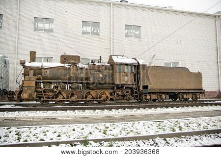 Old rusty steam train locomotive on railroad in winter