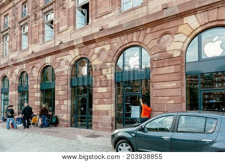 STRASBOURG FRANCE - SEP 9 2014: Customers waiting outside Apple Store prior the launch day of the newest iPhone Apple Watch iPad iMac computers - large Apple Store facade with computer Apple logotype