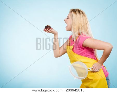 Diet sweets food concept. Woman holding delicious chocolate cupcake with peanut frosting about to take bite