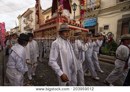April 14, 2017 Cotacachi, Ecuador: indigenous kechwa men walking with religious float on their shoulder at Easter procession