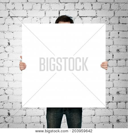 man holding blank paper on brick background