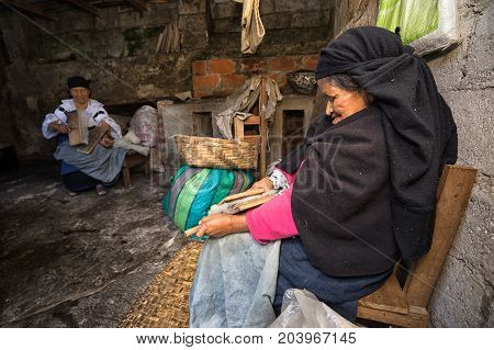 April 21 2017 Iluman Ecuador: elderly quechua woman combing natural wool for hat manufacturing in her home