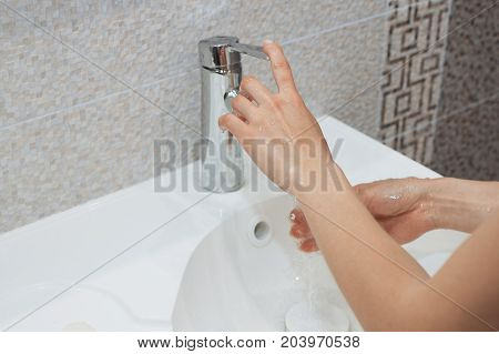Washing of hands with soap under running water.