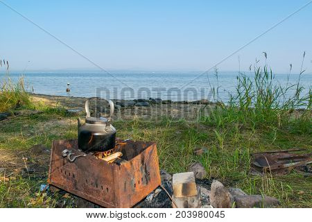 Bloated teakettle on a fire at a bank of a lake - hiking landscape,  Uveldy, The Urals, Russia