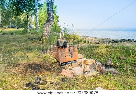 Bloated teakettle on a fire at a bank of a lake - hiking landscape,  Uveldy, The Urals, Russia