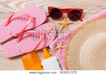 Flip Flops, Straw Hat, Starfish, Sunscreen Bottle, Body Lotion Spray On Wooden Background Top View .