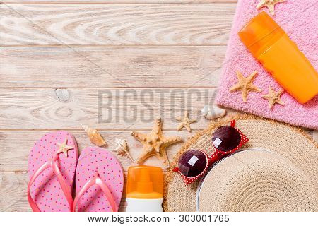 Flip Flops, Straw Hat, Starfish, Sunscreen Bottle, Body Lotion Spray On Wooden Background Top View .
