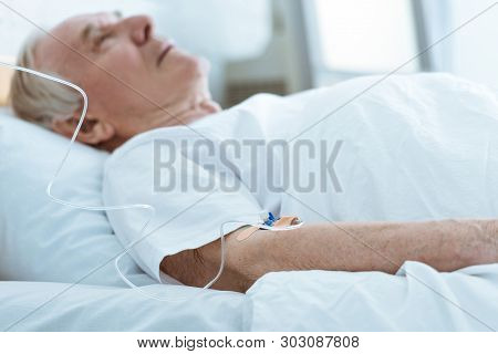 Selective Focus Of Senior Unconscious Man Lying On Bed In Hospital