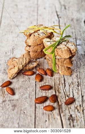 Fresh Italian cookies cantuccini stackes and almond seeds on ructic wooden table background. Sweet food.