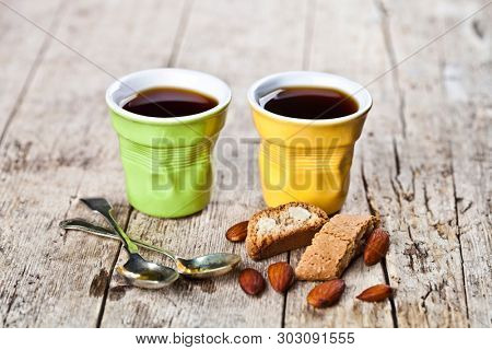Two cups of coffee, fresh Italian cookies cantuccini and almond seeds on ructic wooden table background. Italian breakfast.