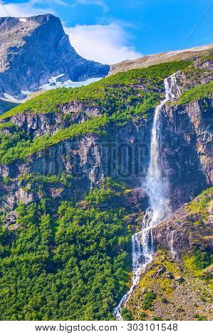 Waterfall, Mountain Cliff And Green Trees On The Way To Briksdal Or Briksdalsbreen Glacier In Olden,