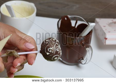 A Woman Decorates With The Help Of White Chocolate Popcake Glazed With Dark Chocolate.