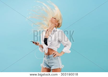 Young Slender Blond Girl With Long Hair Listens To Music On Headphones And Dances, Throws Back Her H