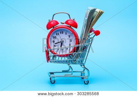 Red Retro Alarm Clock And Dollar Bills In Shopping Cart On Blue Background. Shopping Time, Market, C