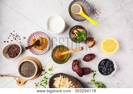 Flt Lay Of Super Foods - Honey, Dates, Milk, Turmeric, Lemon, Nuts And Chia On A White Background. C