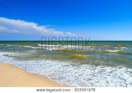 Sea Waves Wash The Beach Against A Blue Sky. Landscape On A Wild Beach. The Sea In The Summer.