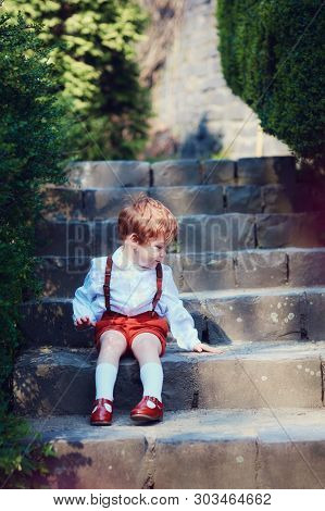 Cute Redhead Baby Boy Sitting On Trairs In Spring Garden
