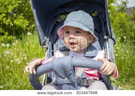 Smiling Baby Girl 9 Months In Panama Walks In A Stroller. A Child In A Good Mood Portrait Close-up. 