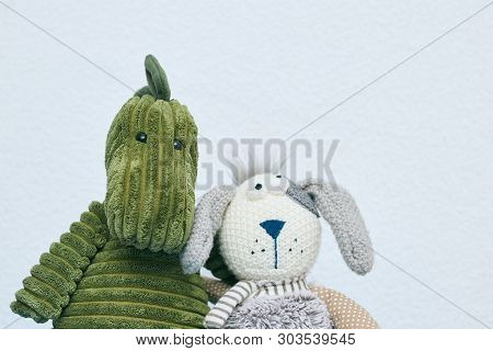 Gray Rabbit And Green Dinosaur Plush Toys For Children On A Light Background. Horizontal View. Copy 