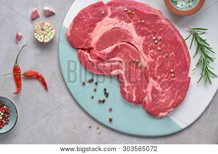 Raw Steak. Meat With Spices And Herbs. Top View On Light Stone Background.