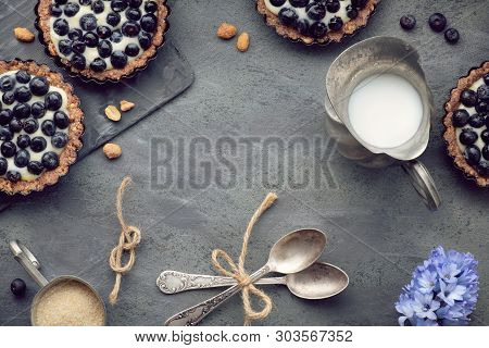 Top View On Wholegrain Blueberry Tarts With Vanilla Cream And Hyacinth Flowers On Dark Background