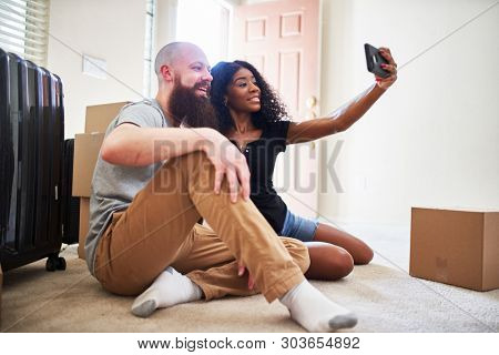 interracial couple taking selfie together while moving into new home