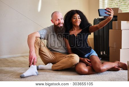 interracial couple taking selfie together while moving into new home
