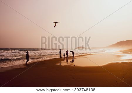 Karpasia, Cyprus - 14 April, 2019: Atmospheric Capture Of Silhouettes Of People Playing And Flying A