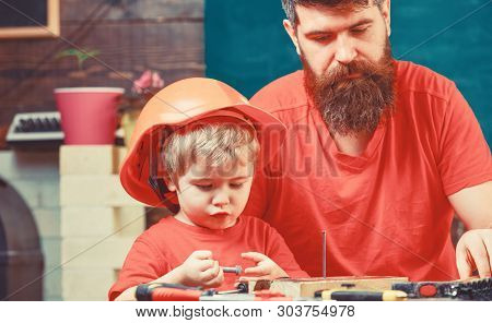 Masculine Duties Concept. Boy, Child Busy In Protective Helmet Learning To Hammering Hobnails With D
