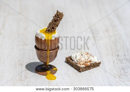 Soft Boiled Egg In Eggcup With Slice Of Toasted Toast On White Wooden Table Background