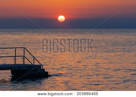 Old Pier On Croatian Coast And Setting Sun In Background. Tourism, Travel And Vacation Concepts