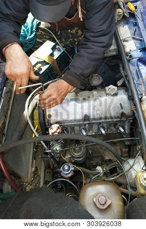 The Car Mechanic Unlocks The Motor Cover Of An Old Car And Will Repair It.