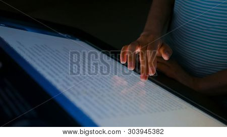 Woman Using Interactive Touchscreen Display In Modern Historical Museum. Evening Time, Lowlight. Edu