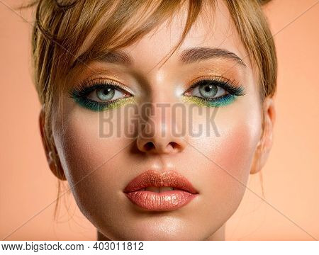 Beautiful girl with trandy makeup. Face of an young girl close-up with a green color makeup. Stylish makeup.