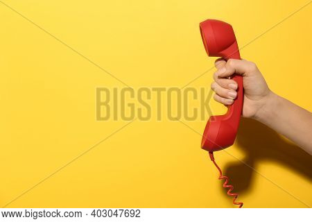 Closeup View Of Woman Holding Red Corded Telephone Handset On Yellow Background, Space For Text. Hot