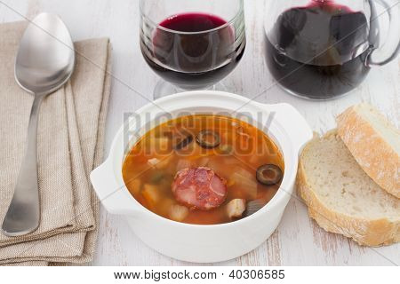 Köttsoppa i skålen med sked, bröd och rött vin