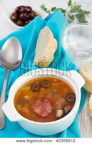 Suppe med Saisages og oliven i skålen med glas vand