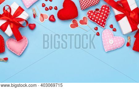Valentines day greeting card template. Gift boxes, heart decor and candy sweets over blue background. Top view flat lay with copy space