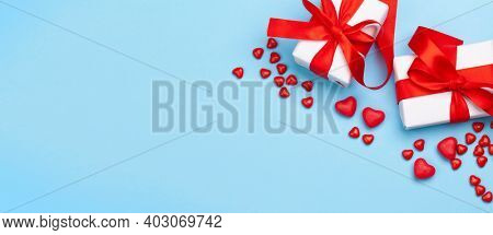 Valentines day greeting card template. Gift boxes and heart candy sweets over blue background. Top view flat lay with copy space