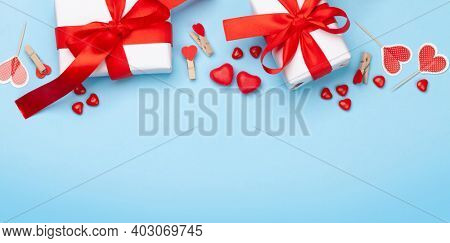 Valentines day greeting card template. Gift boxes, heart decor and candy sweets over blue background. Top view flat lay with copy space