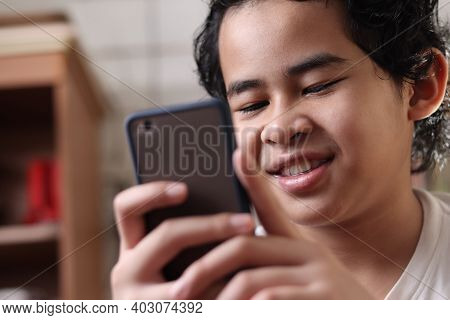 Portrait Of Asian Boy Using His Smart Phone, Student In Library, Close Up