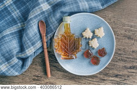 Maple syrup rustic table top view canadian natural product from Canada. Maple leaf shape gift bottle, soft candy and hard candy taffy candies kitchen cooking.