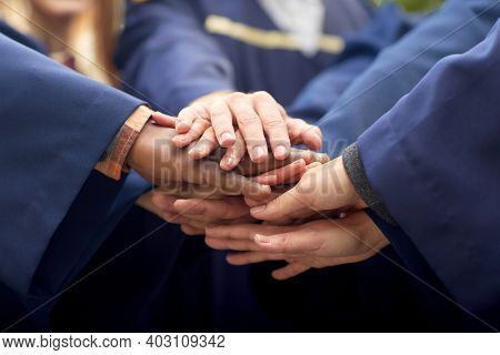 education, graduation and people concept - close up of inernational graduate students stacking hands