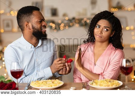 Proposal Fail. Portrait Of Unhappy African American Man Proposing To His Gilfriend, Holding Open Box