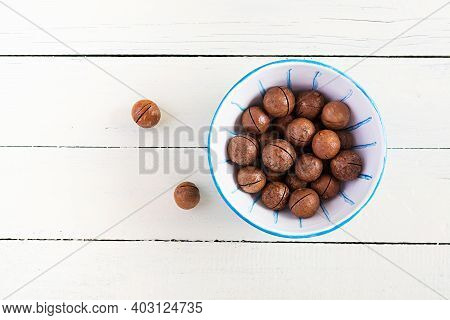 Organic Macadamia Nuts (macadamia Integrifolia) In Shell On Wooden White Table. Top View, Overhead, 